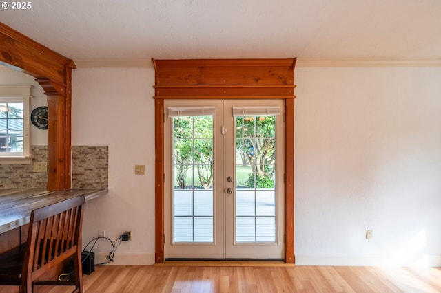 doorway to outside featuring crown molding, baseboards, wood finished floors, and french doors