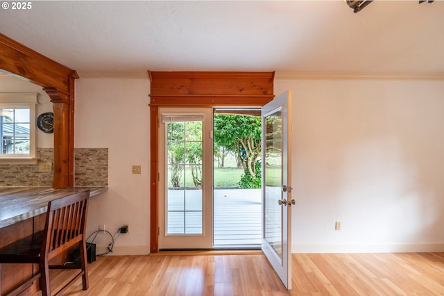 entryway with plenty of natural light, ornamental molding, and wood finished floors