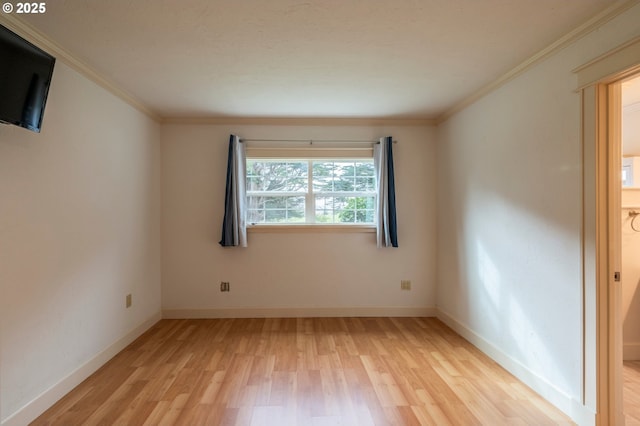 spare room with crown molding, light wood-style flooring, and baseboards