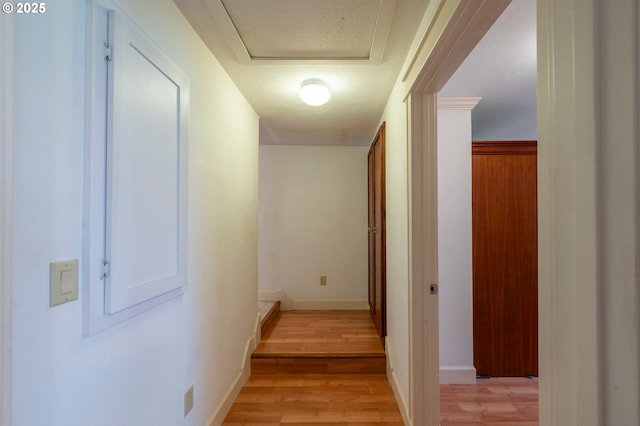 hall featuring attic access, light wood-style flooring, and baseboards