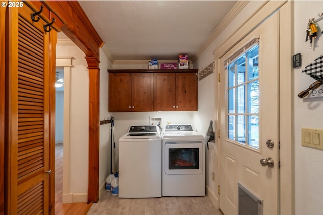 clothes washing area with washing machine and clothes dryer, cabinet space, light wood-style flooring, ornamental molding, and baseboards