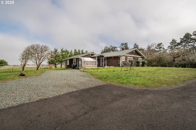 view of front of house with a chimney, an outbuilding, gravel driveway, an exterior structure, and a front yard