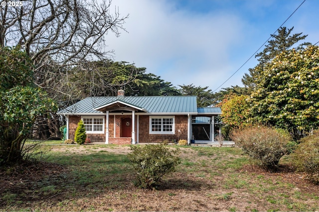 view of front of home featuring a standing seam roof, a chimney, metal roof, and a front yard