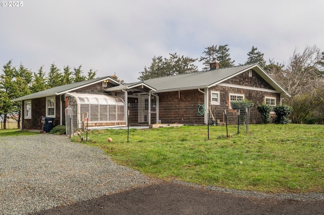 view of front facade with a front yard, metal roof, and a chimney