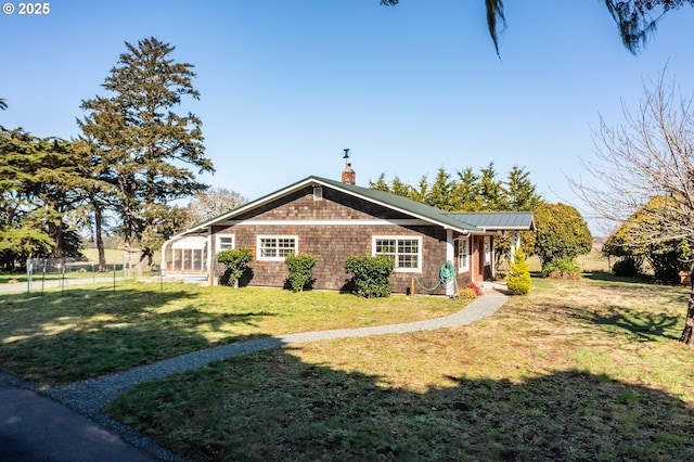 view of front of home with a front yard, metal roof, fence, and a chimney