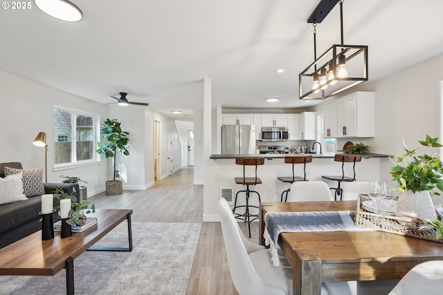 living room featuring sink, ceiling fan, and light hardwood / wood-style flooring