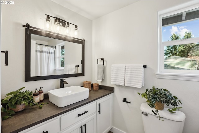 bathroom featuring a shower with curtain, plenty of natural light, toilet, and vanity