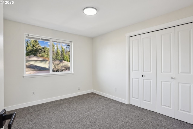 unfurnished bedroom with a closet and dark colored carpet