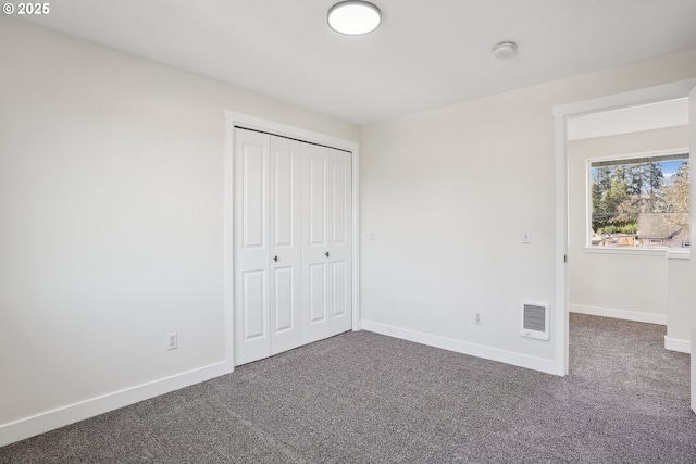 unfurnished bedroom with dark carpet and a closet