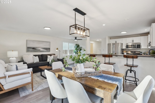 dining area featuring ceiling fan, sink, and light wood-type flooring