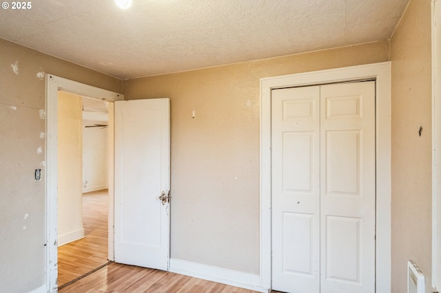 unfurnished bedroom with baseboards, a closet, and light wood finished floors