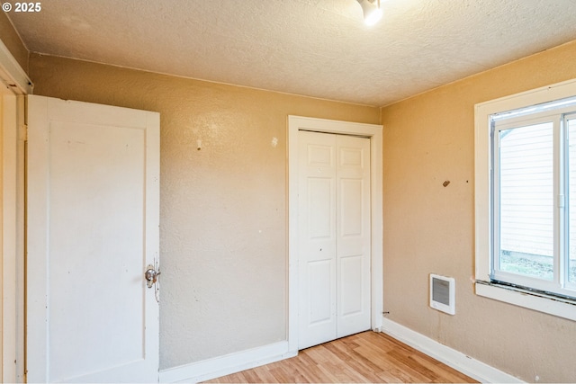 unfurnished bedroom featuring a closet, visible vents, light wood-style flooring, and baseboards