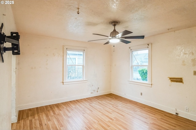 unfurnished room with wood finished floors, baseboards, a wealth of natural light, and a textured ceiling