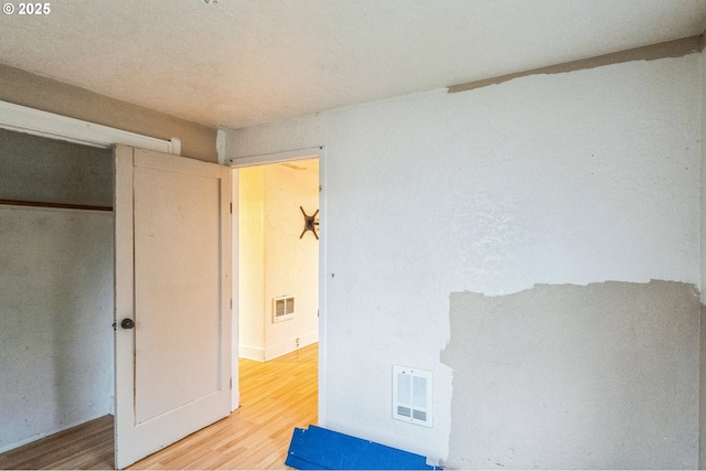 unfurnished bedroom with wood finished floors and visible vents