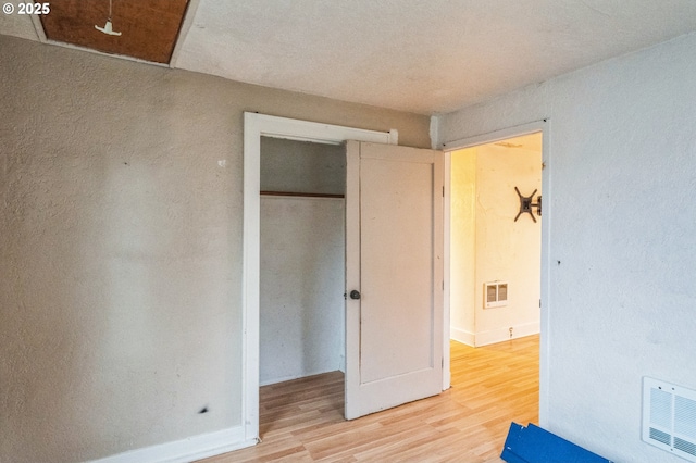 unfurnished bedroom featuring light wood-style floors, visible vents, a closet, and baseboards