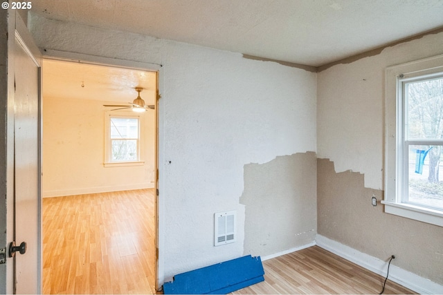 unfurnished room with visible vents, plenty of natural light, and wood finished floors