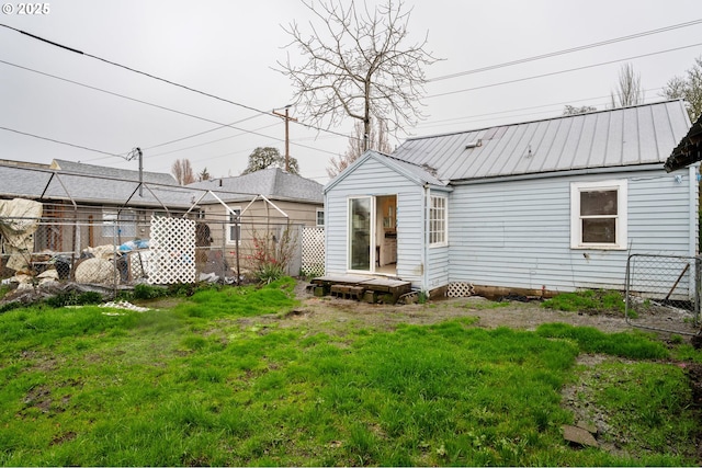 rear view of property featuring a yard, metal roof, and fence