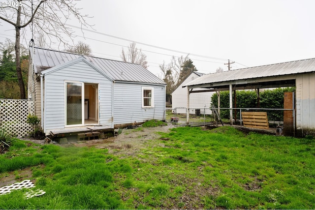 back of property with a gate, a standing seam roof, fence, a yard, and metal roof