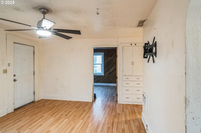 spare room featuring light wood finished floors, visible vents, and baseboards