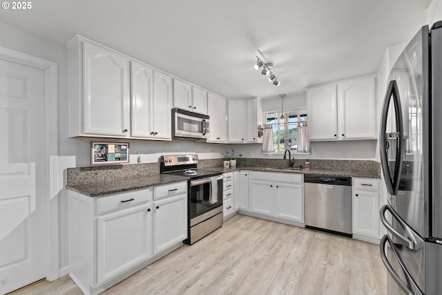 222 NE Darcie Way, Myrtle Creek, OR 97457 - kitchen featuring stainless steel appliances, a sink, light wood-style floors, white cabinetry, and dark stone counters