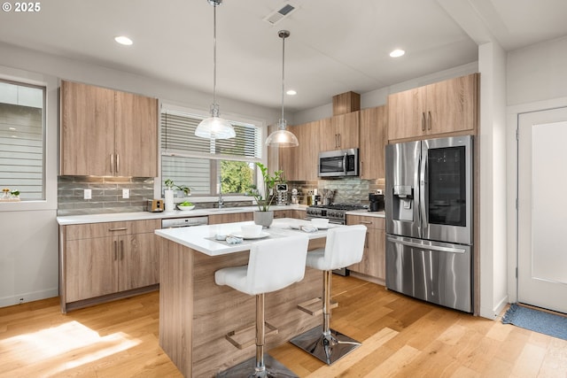 kitchen featuring a breakfast bar area, backsplash, visible vents, appliances with stainless steel finishes, and light wood-type flooring