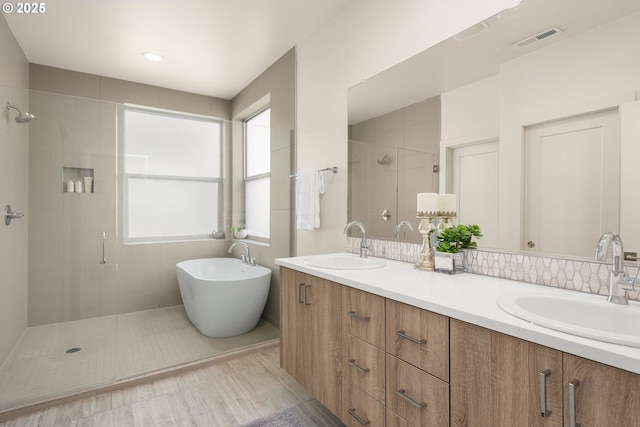 full bathroom featuring a sink, a stall shower, double vanity, and visible vents