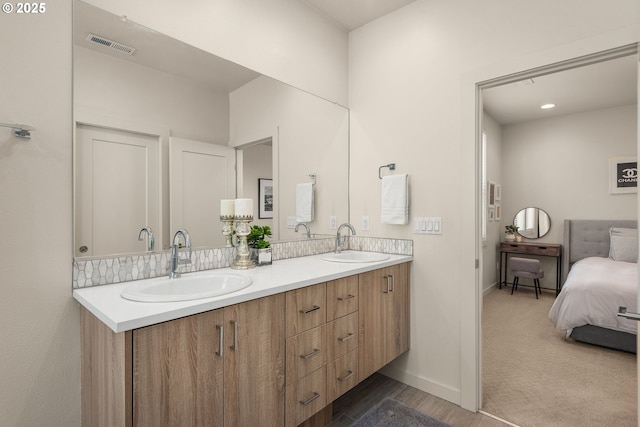 ensuite bathroom featuring double vanity, baseboards, visible vents, and a sink