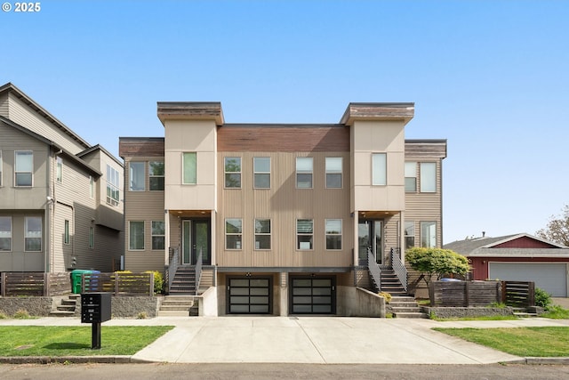 multi unit property featuring an attached garage, concrete driveway, and stairway