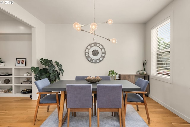 dining room featuring light wood-type flooring, baseboards, and an inviting chandelier