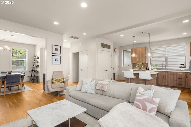 living room featuring visible vents, recessed lighting, light wood finished floors, and a notable chandelier