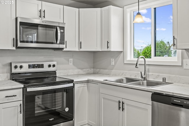 kitchen with decorative light fixtures, sink, stainless steel appliances, white cabinets, and light stone counters