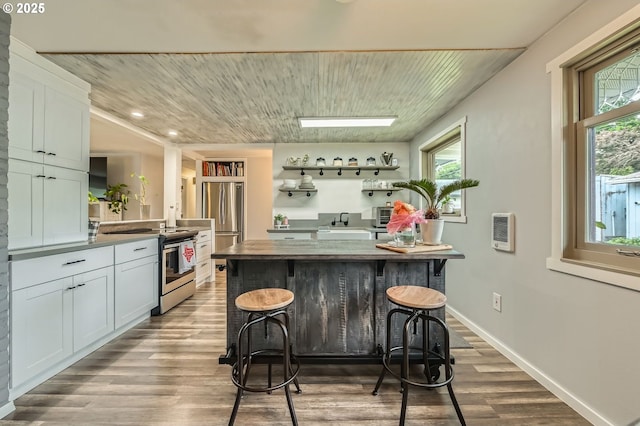 8413 NE Lewis Dr, Vancouver, WA 98662 - kitchen featuring stainless steel appliances, a breakfast bar area, wood finished floors, white cabinetry, and baseboards