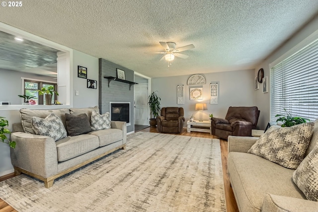 8413 NE Lewis Dr, Vancouver, WA 98662 - living room with wood finished floors, plenty of natural light, a ceiling fan, a large fireplace, and a textured ceiling