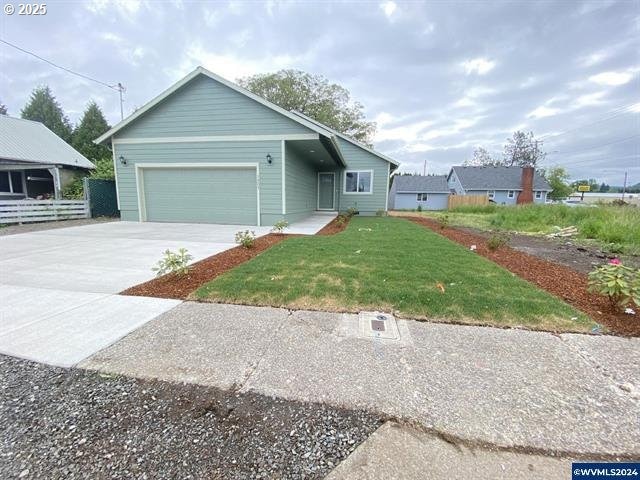 view of front facade with a garage, concrete driveway, and a front lawn