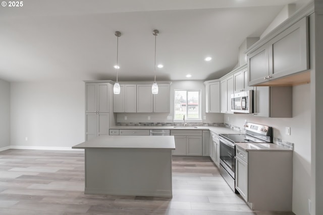 kitchen featuring appliances with stainless steel finishes, pendant lighting, light countertops, and a sink