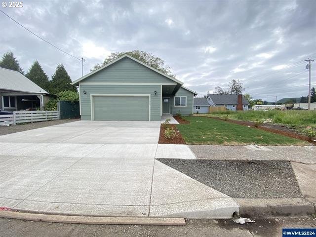 view of front of property with a front yard, driveway, an attached garage, and fence