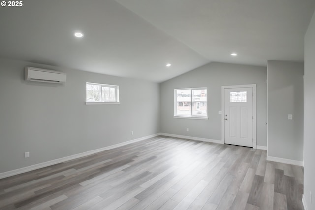 interior space with an AC wall unit, plenty of natural light, and wood finished floors