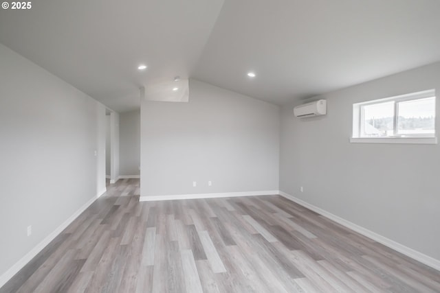 unfurnished room featuring light wood-type flooring, an AC wall unit, baseboards, and recessed lighting