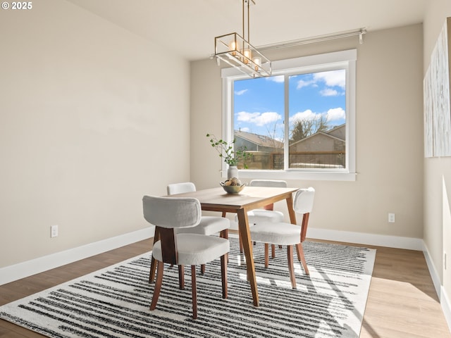 dining room featuring a chandelier, baseboards, and wood finished floors