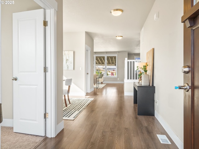 corridor with baseboards, visible vents, and dark wood finished floors