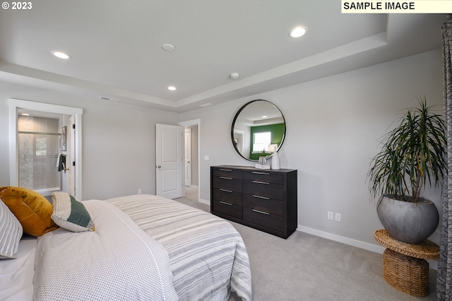 carpeted bedroom featuring ensuite bathroom and a tray ceiling