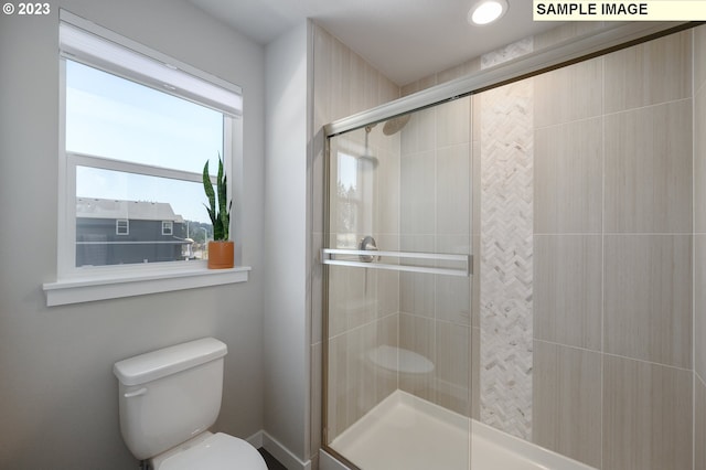 bathroom featuring a shower with shower door and toilet