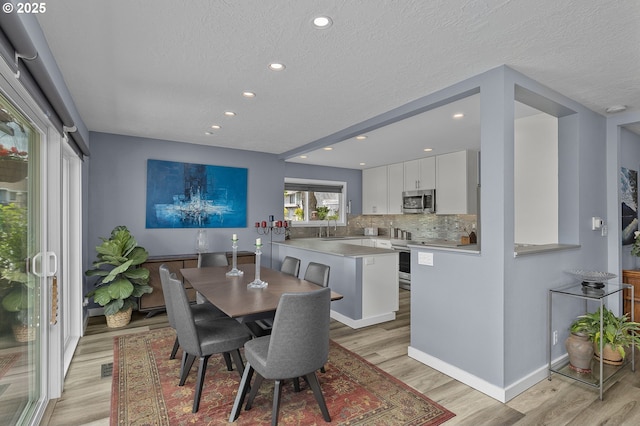 620 N Hayden Bay Dr, Portland, OR 97217 - dining area with light wood finished floors, a textured ceiling, recessed lighting, and baseboards