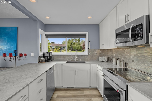 620 N Hayden Bay Dr, Portland, OR 97217 - kitchen with appliances with stainless steel finishes, a sink, decorative backsplash, white cabinetry, and recessed lighting