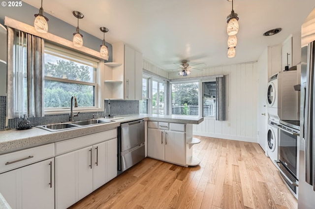 1805 NE Saratoga St, Portland, OR 97211 - kitchen featuring a sink, stacked washer and clothes dryer, stainless steel dishwasher, open shelves, and healthy amount of natural light