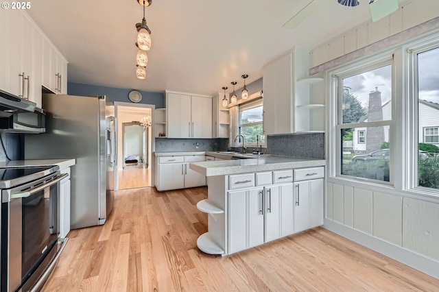 1805 NE Saratoga St, Portland, OR 97211 - kitchen featuring open shelves, a peninsula, appliances with stainless steel finishes, and light wood-type flooring