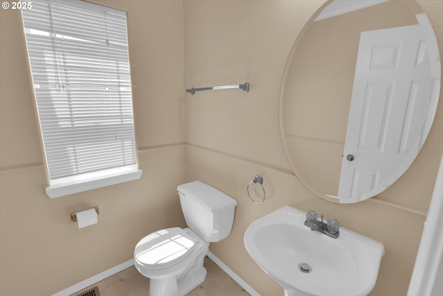 half bath with a sink, toilet, and baseboards
