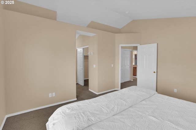 bedroom featuring carpet, lofted ceiling, baseboards, and a walk in closet
