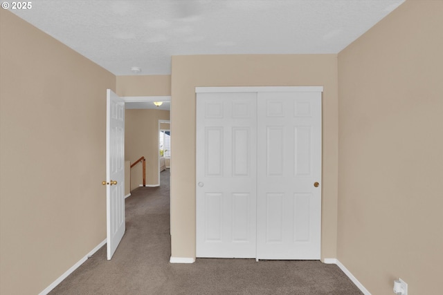 unfurnished bedroom with carpet flooring, baseboards, and a closet