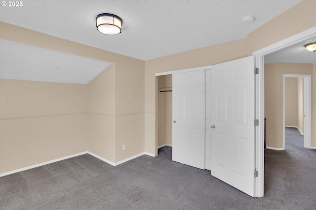 unfurnished bedroom with dark carpet, baseboards, a closet, and a textured ceiling